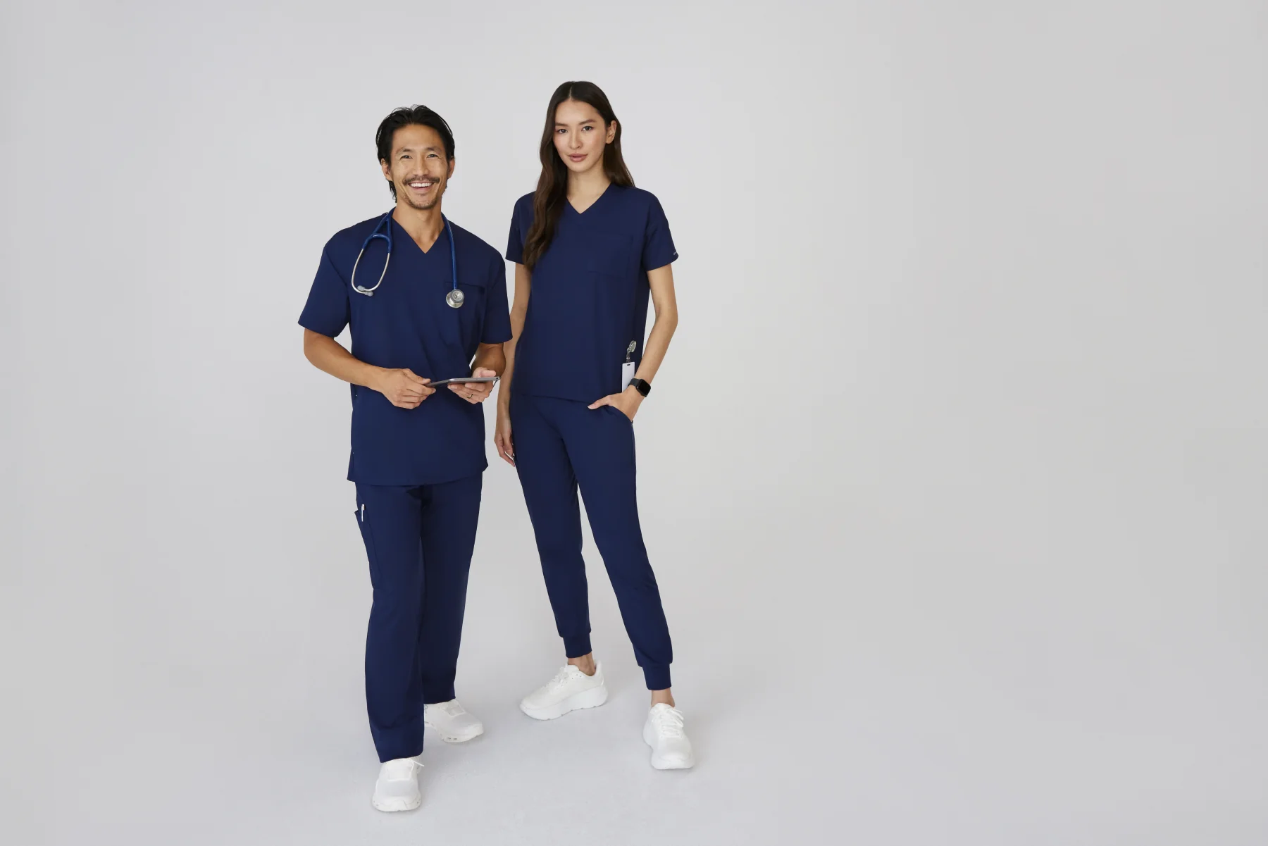 Male and female healthcare professionals wearing navy scrubs, highlighting Scrubs By Design's variety and inclusivity